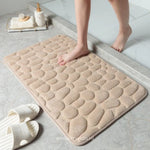 Voeten van een persoon op een beige badmat in een moderne badkamer met badkameraccessoires