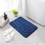 Blauwe badmat in een moderne badkamer met witte slippers en badkameraccessoires.