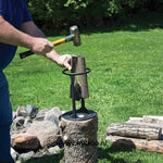 Man met hamer in de tuin met de slag houtkloofmachine die splijt een stuk hout