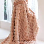 Vrouw gehuld in roze fluffy deken bij raam