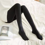 Zwarte panty met gesloten tenen, dame zit op bed.