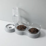 Grijze voedertray met waterdispenser en voerbakken.