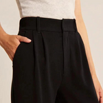foto van vrouw in zwarte wijde pantalon gezien vanaf de middel en heeft haar hand in de steekzak.