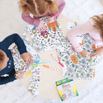 Kinderen kleuren inkleurbare pyjama's aan een tafel.