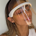 Vrouw draagt LumiGlow LED masker met oranje licht voor huidverbetering.